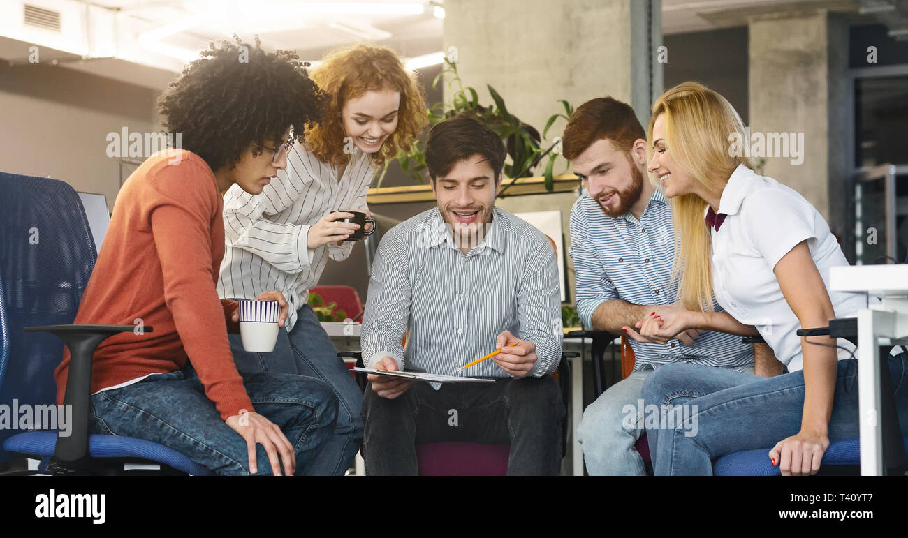 Gruppo di giovani colleghi discutendo nuove strategia di marketing in ufficio Foto Stock