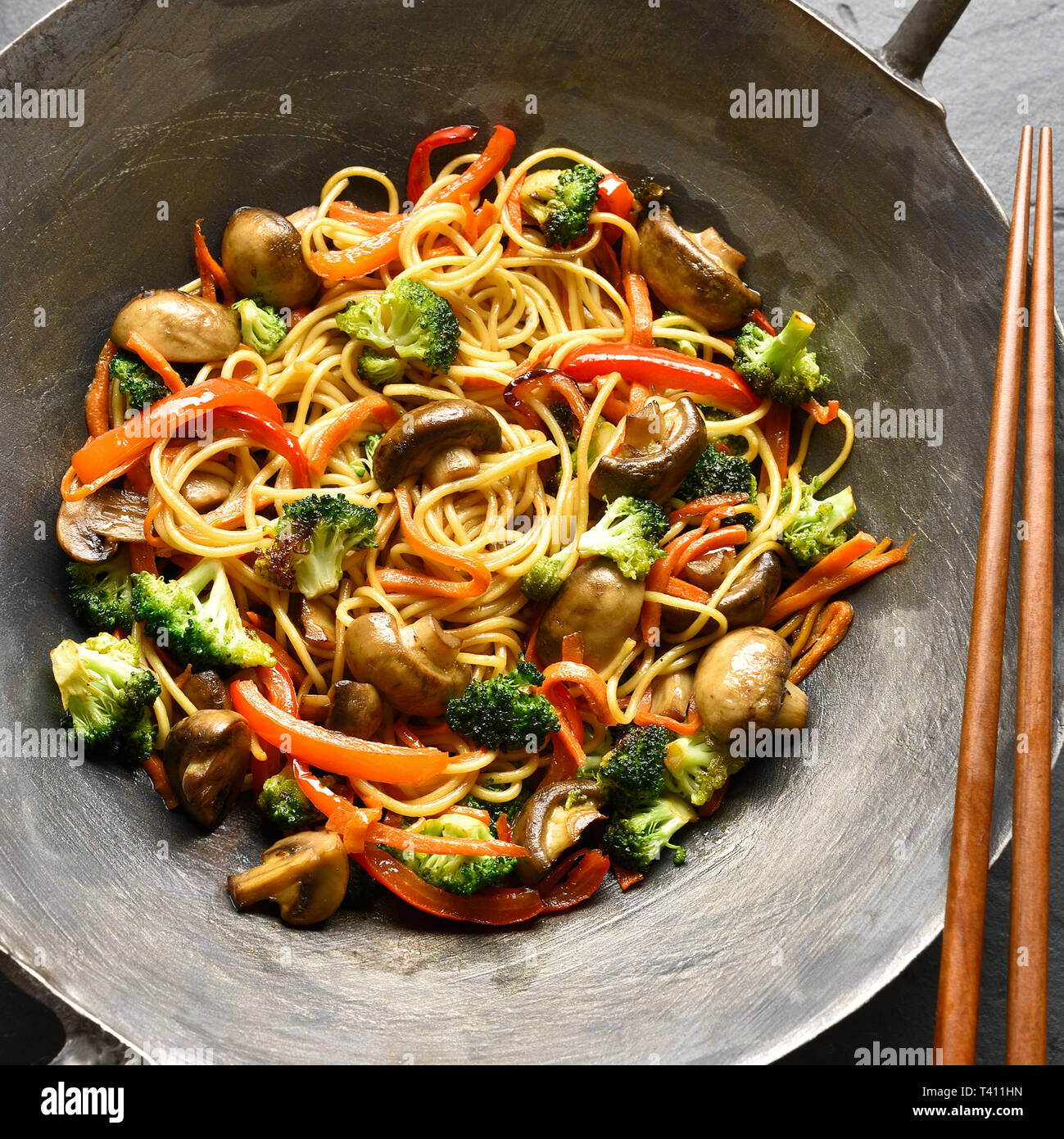 Close up di mescolare verdure fritte con tagliatelle in padella wok. Vista superiore, laici piatta Foto Stock