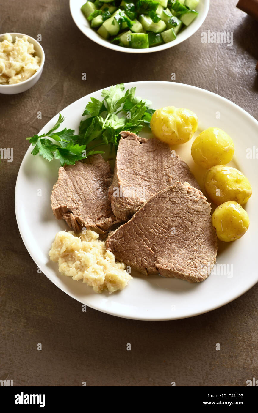 Tafelspitz, bollito di manzo con patate e rafano su sfondo marrone. Slow manzo cotto con verdure Foto Stock