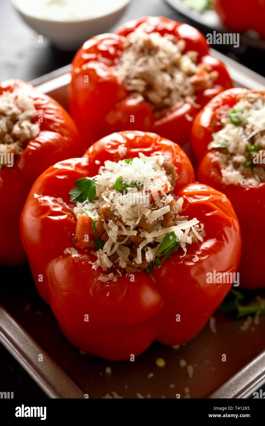Close up farcito di peperoni rossi con carne macinata, riso, cipolla, formaggio parmigiano. Gustoso piatto per la cena Foto Stock
