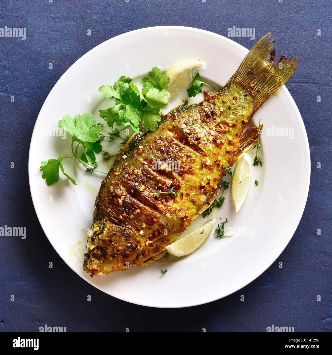 Close up di grigliate di pesce sulla piastra su pietra blu sullo sfondo. Frutti di mare. Gustoso pesce al forno per la cena. Vista superiore, laici piatta Foto Stock