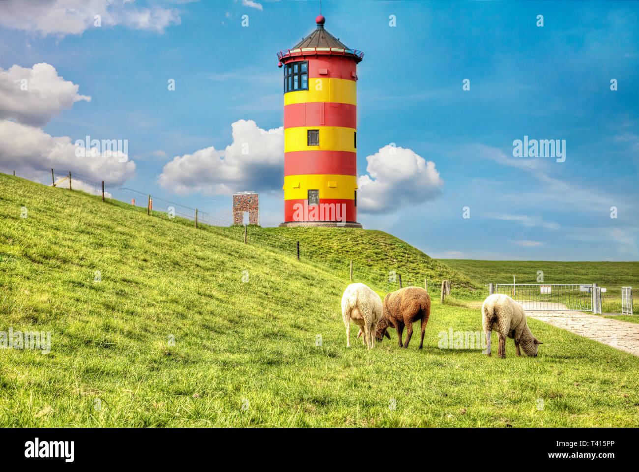 Le pecore di fronte al Pilsum faro sulla costa del Mare del Nord della Germania. Foto Stock