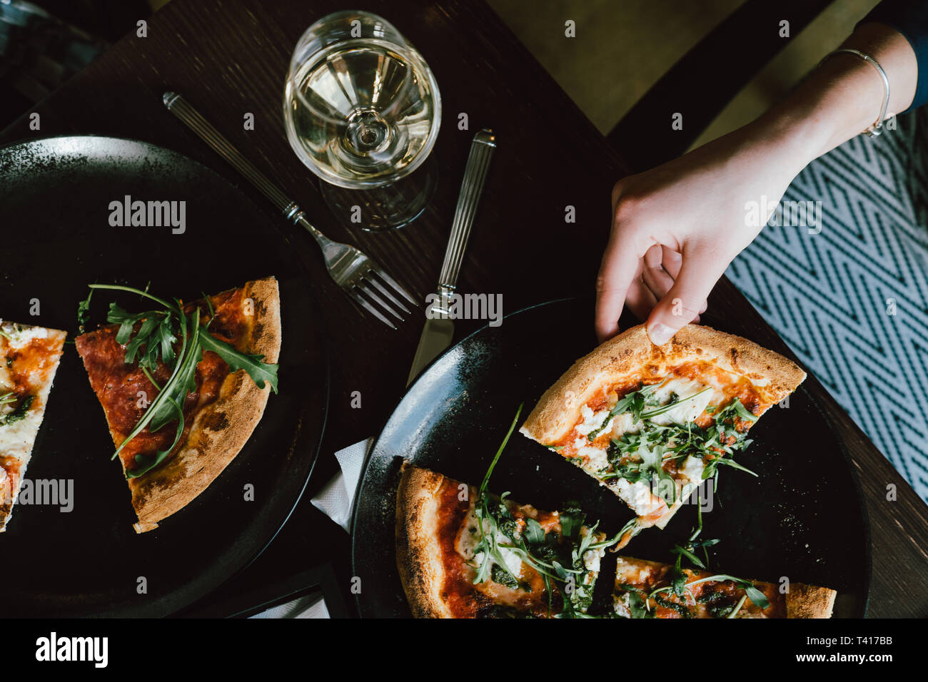 Donna seduta a tavola a mangiare la pizza Foto Stock