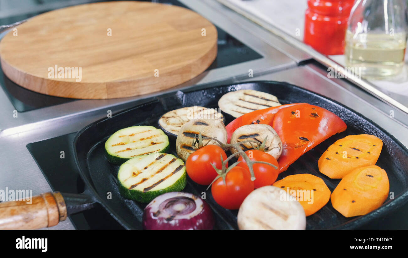 Un lavoro dello chef in cucina. Riscaldamento dei funghi e verdure in padella senza olio Foto Stock