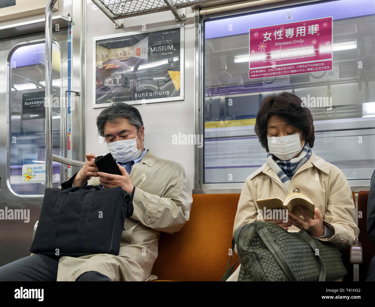Passeggeri della Tokyo metropolitana indossando maschere viso, una visione comune a Tokyo in Giappone Foto Stock