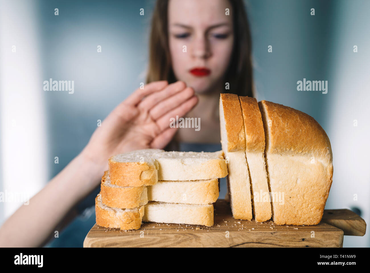 Intolleranza al glutine e concetto di dieta. Giovane ragazza si rifiuta di mangiare il pane bianco. Profondità di campo. Messa a fuoco selettiva su pane Foto Stock