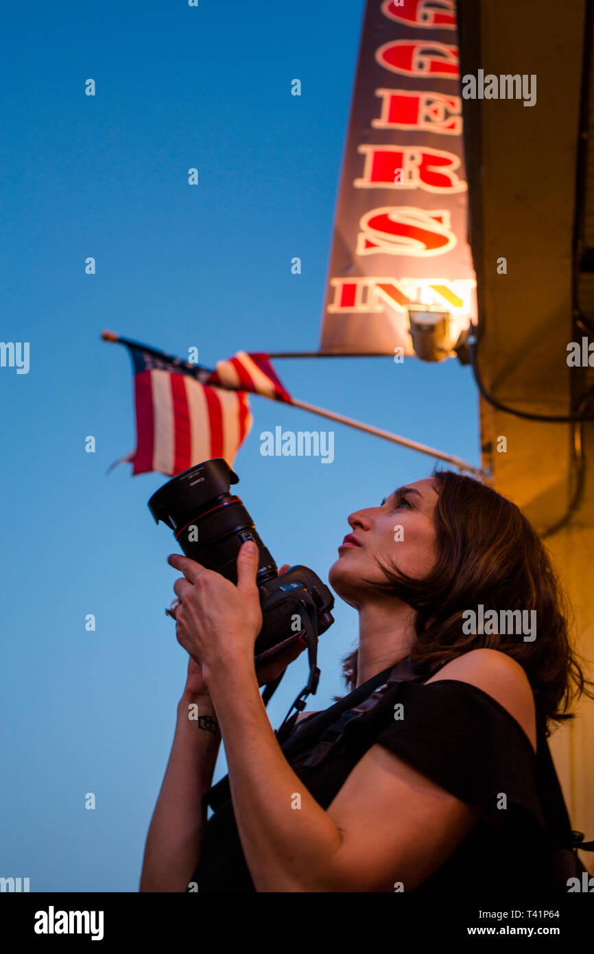 Una donna fotografo sta nel profilo al crepuscolo e guarda il framing shot Foto Stock