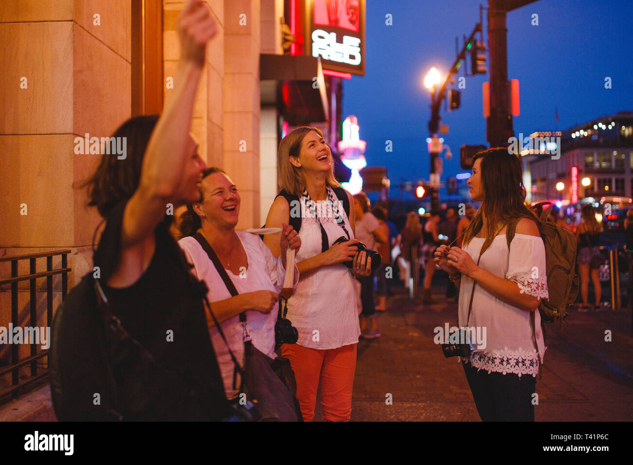 Un gruppo di donna felice turisti celebrare in una trafficata strada di città Foto Stock