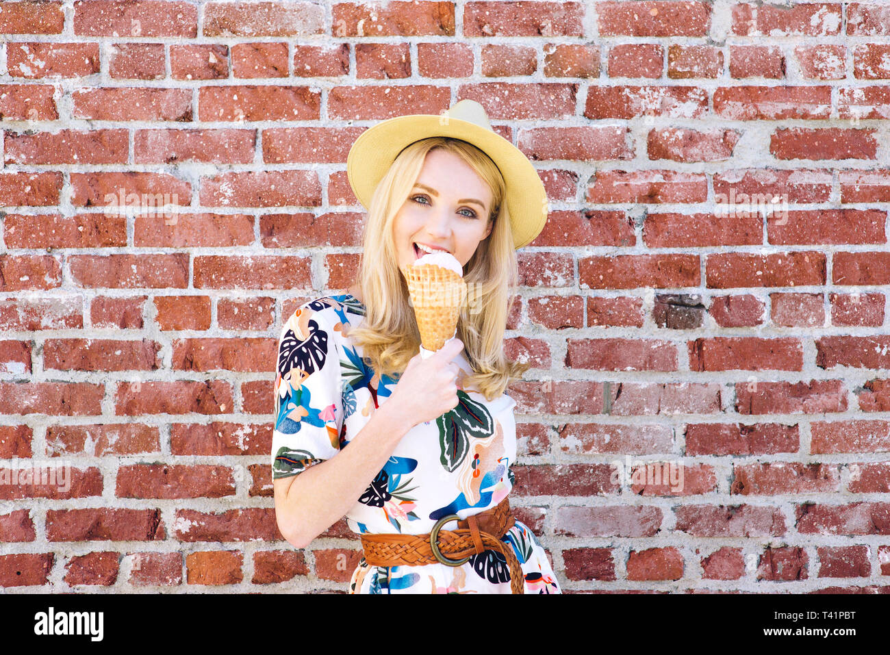 Hip giovane femmina con un cappello Fedora lambisce un gelato in una giornata calda Foto Stock