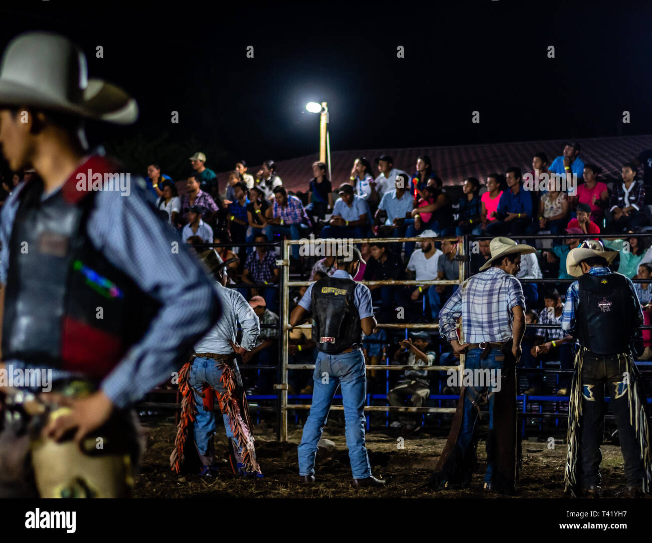 Latin bull riders getting chiamato fuori prima di equitazione in rodeo guatemalteca Foto Stock