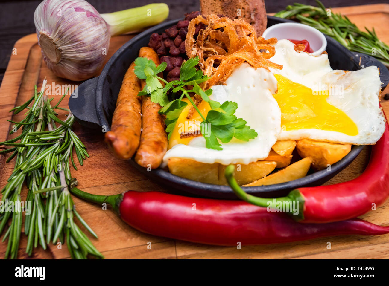 Pasto con uova fritte, salsicce, fagioli, anelli di cipolla, peperoncino e salsa Foto Stock