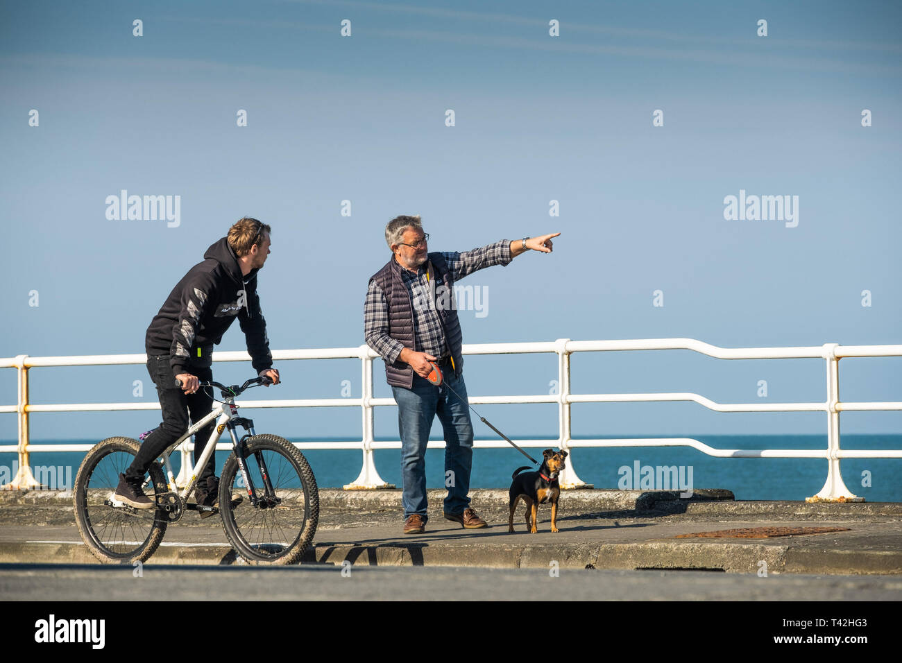 Aberystwyth Wales UK. Il 13 aprile 2019. Regno Unito: Meteo persone sul lungomare su un luminoso snd sunny aprile mattina di primavera con il cielo limpido ma un freddo vento da est che soffia in Aberystwyth su Cardigan Bay costa del Galles occidentale. Credito: Keith Morris/Alamy Live News Foto Stock