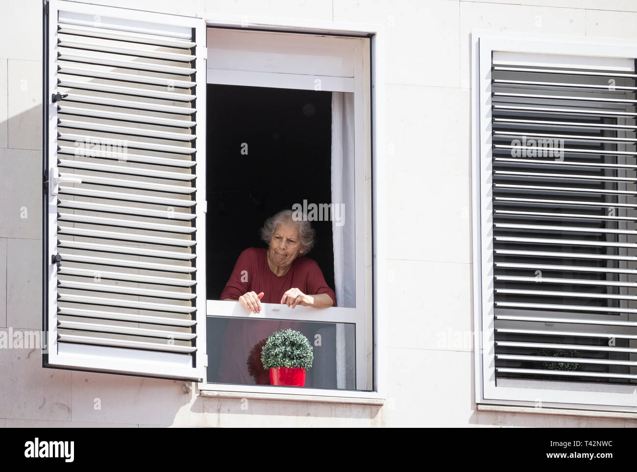 Donna anziana che guarda fuori dalla finestra da un alto edificio in Spagna. Coronavirus, autoisolamento, distanza sociale, quarantena... concetto Foto Stock