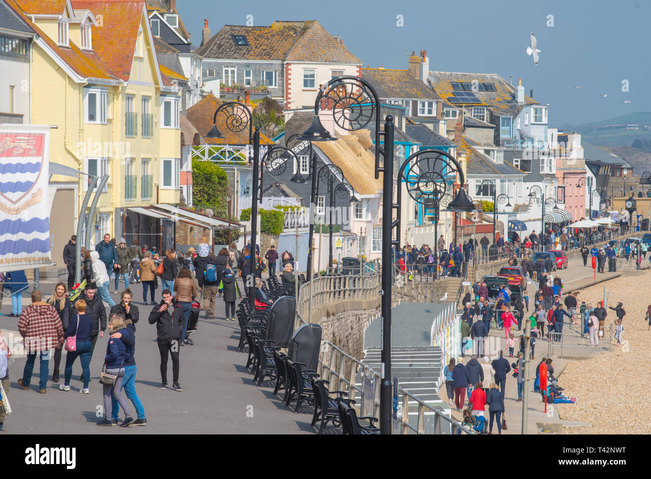 Lyme Regis, Dorset, Regno Unito. Il 13 aprile 2019. Meteo REGNO UNITO: folle di visitatori e famiglie godendo le vacanze scolastiche rendono il meglio di intervalli di sole su un terribilmente freddo e blustery giornata presso il resort costiero di Lyme Regis come gelidi venti da est ha colpito la costa sud. Credito: Celia McMahon/Alamy Live News Foto Stock