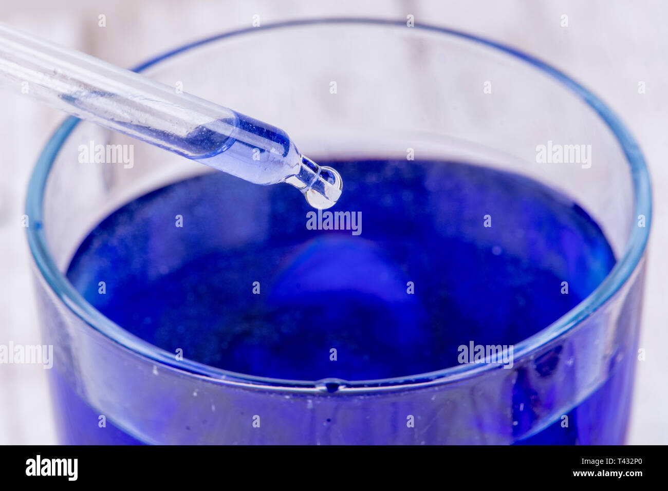Pipetta scende una goccia di liquido in un blu contenitore di liquido Foto Stock