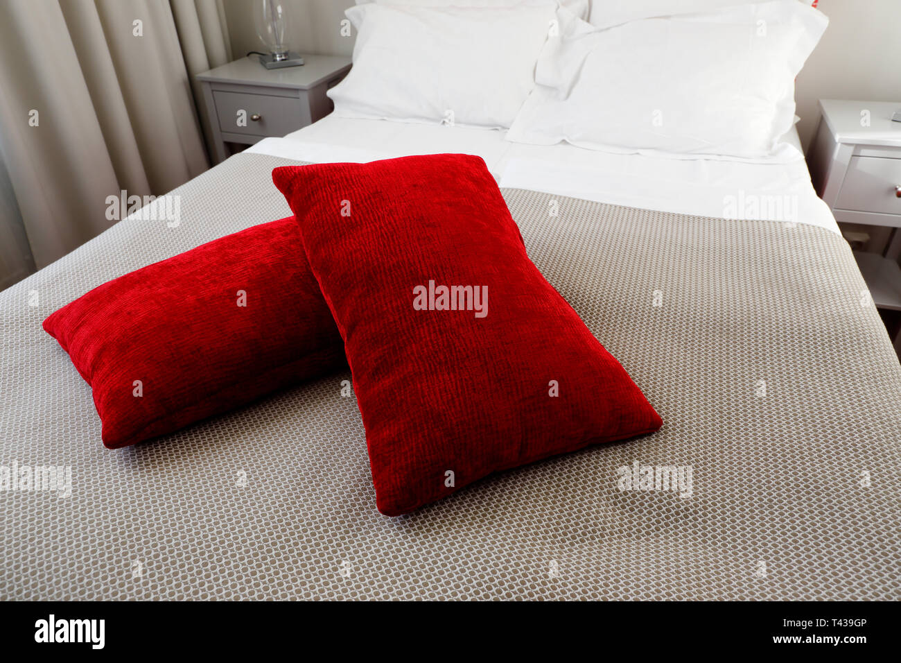 Camera in hotel con due cuscini rosso situato sulla parte superiore del letto. Foto Stock