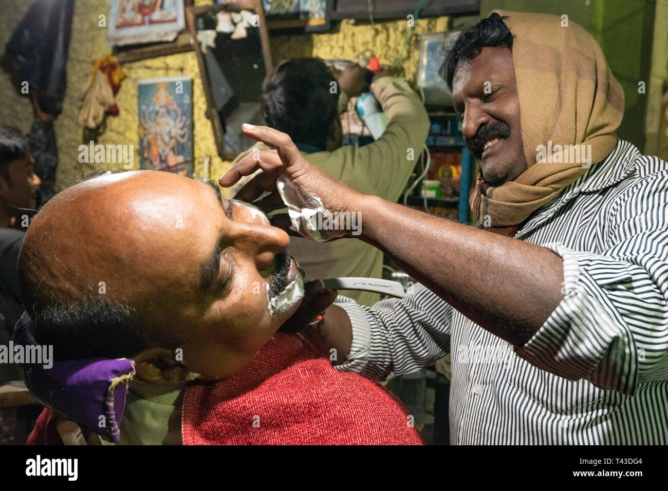 Ritratto orizzontale di un barbiere al lavoro in Kolkata aka Calcutta, India. Foto Stock