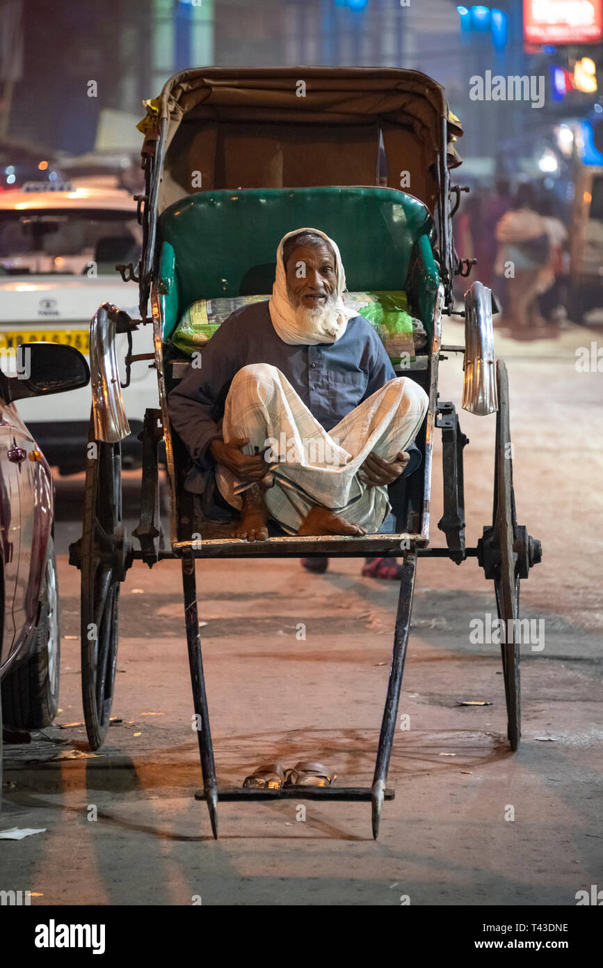 Ritratto verticale tirato un rickshaw proprietario in attesa per il business in Kolkata aka Calcutta, India. Foto Stock