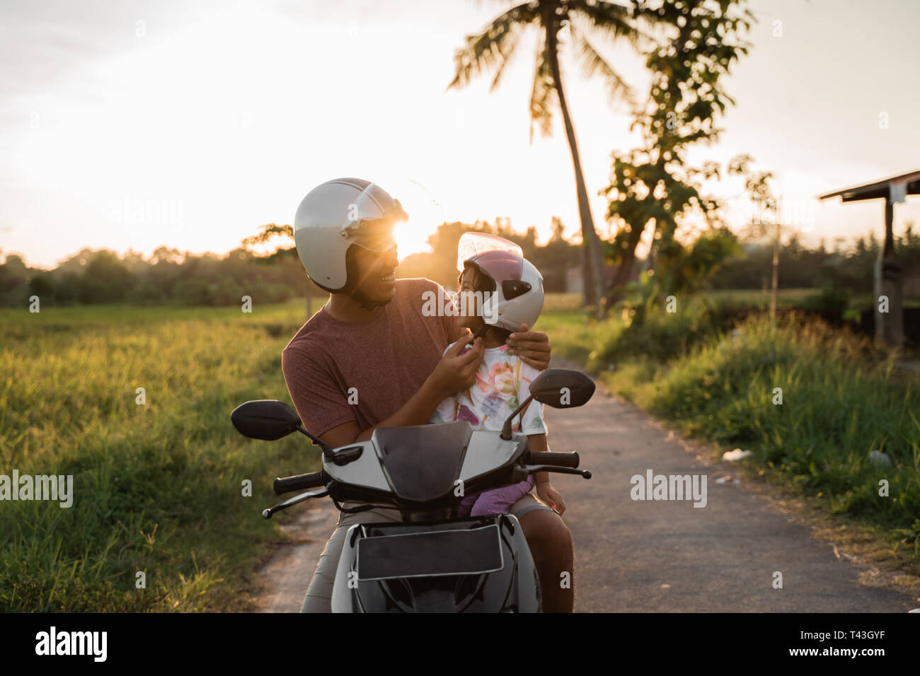 Il daddy aiutare a sua figlia di allacciare il casco durante la guida di un  motociclo scooter Foto stock - Alamy