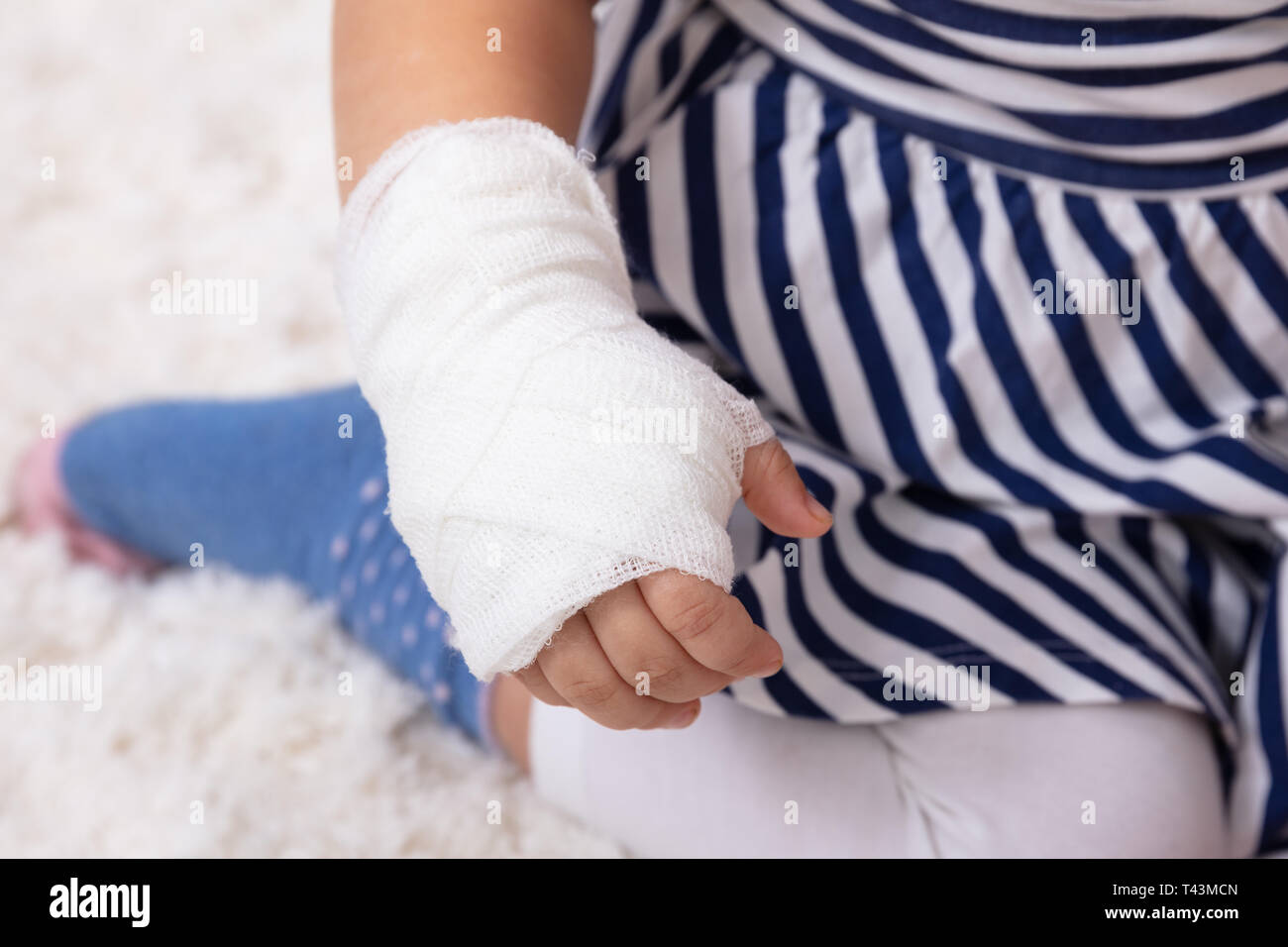 Close-up della bambina con bendaggio sulla sua mano seduti sul divano Foto Stock