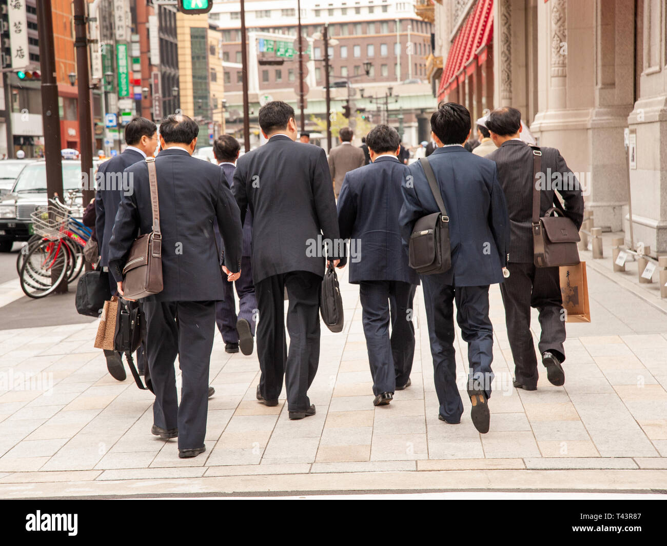 Gruppo di salarymen camminare insieme nel Nihombashi financial district, Tokyo, Giappone Foto Stock