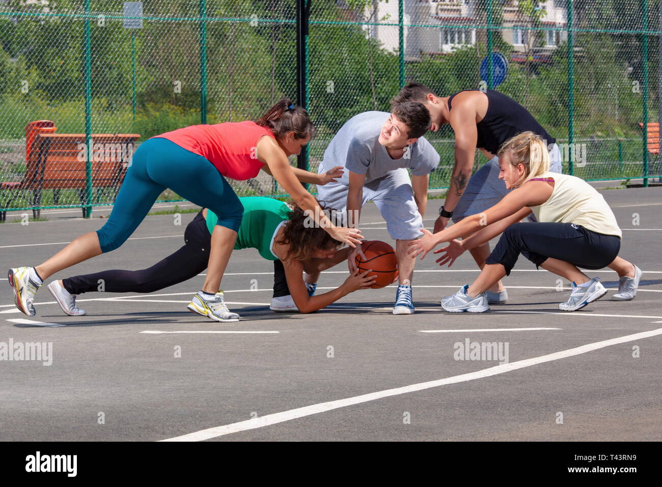 Mescolati i giovani, uomini e donne, giocare a basket su un parco giochi Foto Stock