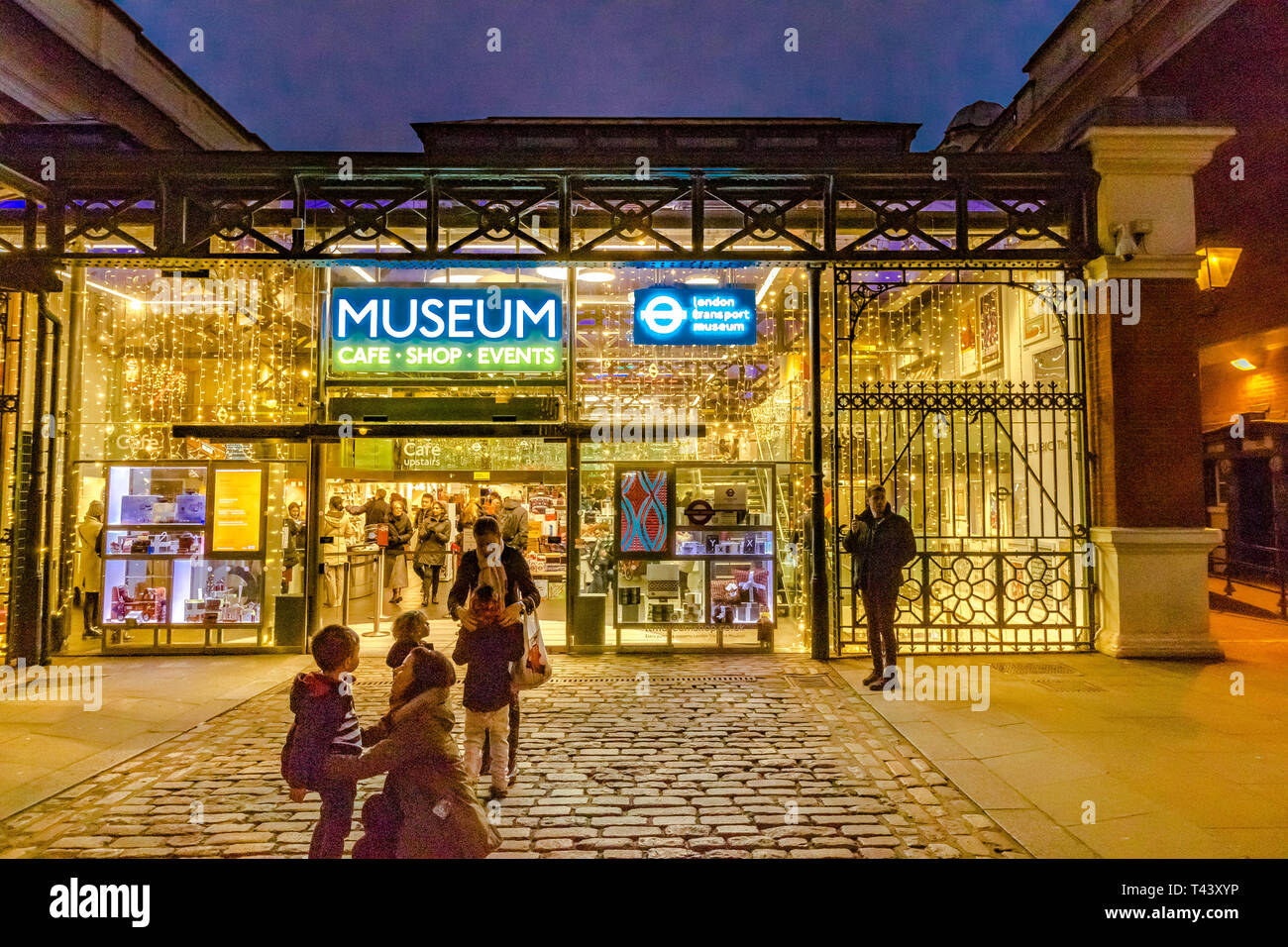 Una famiglia fuori dal London Transport Museum a Covent Garden Piazza di notte, Londra, Regno Unito Foto Stock