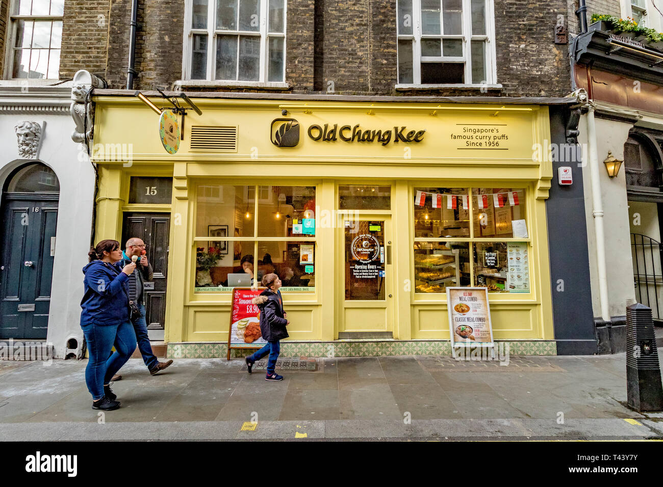 Una famiglia cammina attraverso Old Chang Kee, Londra, un ristorante specializzato nel Singapore curry puff, una versione piccante della pasta Cornish, Londra, Regno Unito Foto Stock