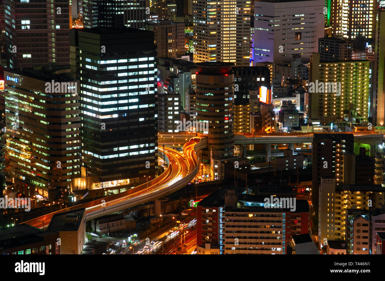 Vista aerea di una autostrada che attraversano un edificio per uffici nel quartiere Umeda di notte. Osaka, Giappone. Foto Stock