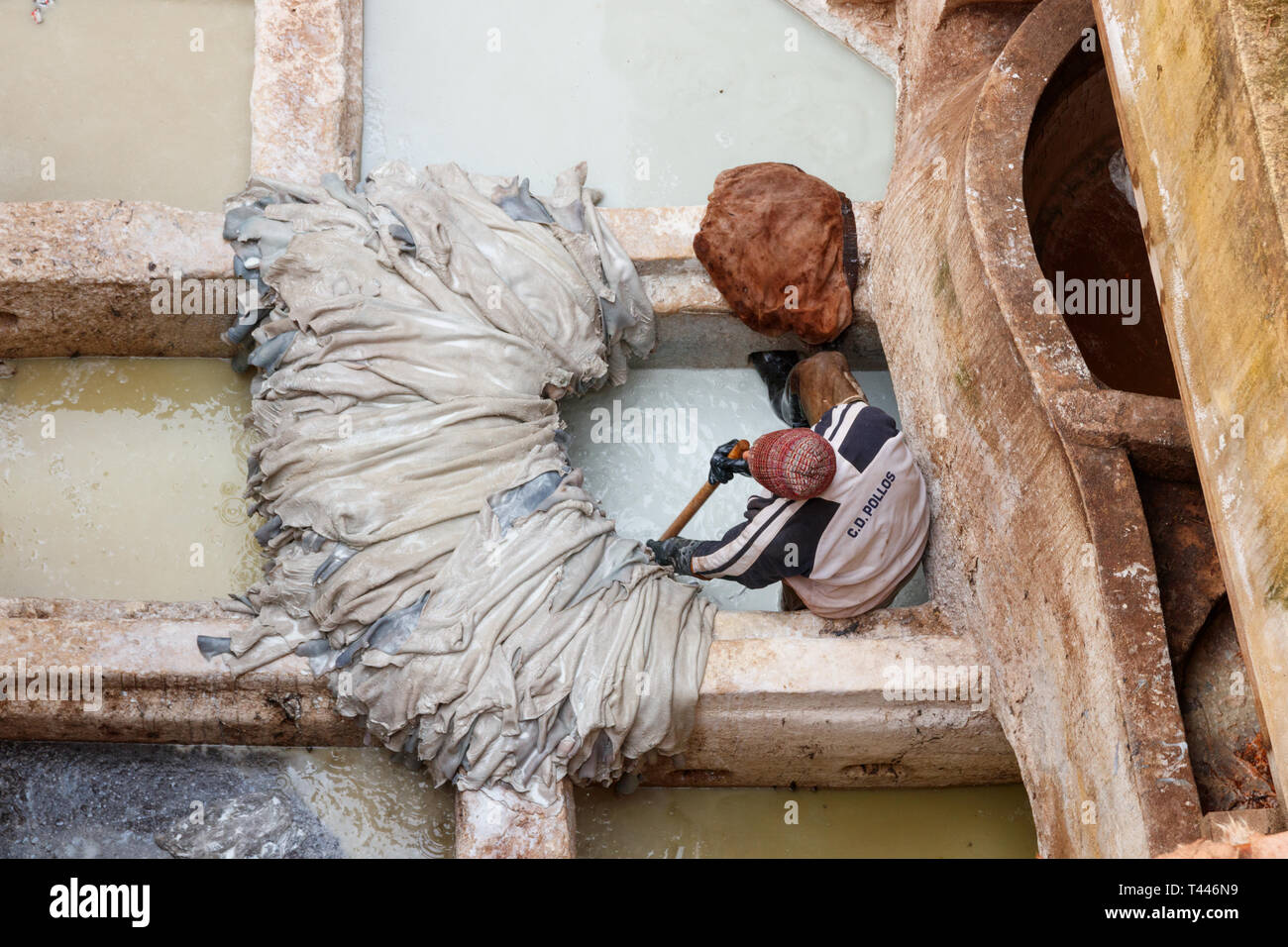 Pile di pelli sul bordo di una vasca e un lavoratore di eseguire il lavoro manuale a Chouara conceria. Fez, in Marocco. Foto Stock