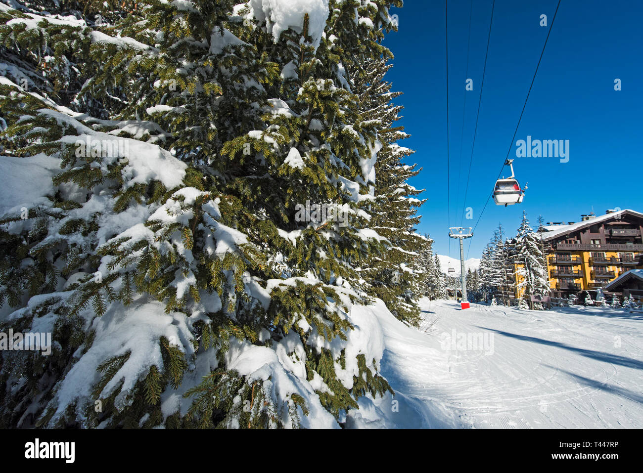 Vista panoramica di una coperta di neve delle piste da sci e gli alberi in una località alpina con funivia sollevare e hotel Foto Stock