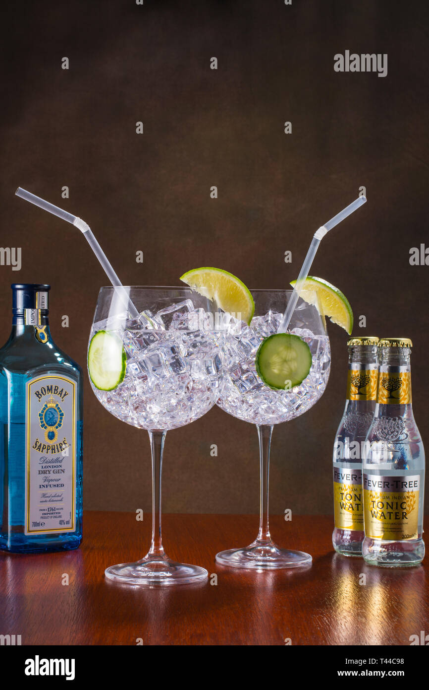 Gin Tonic, stile moderno - globo di vetro, lotti di ghiaccio, fette di cetriolo e calce e una paglia Foto Stock