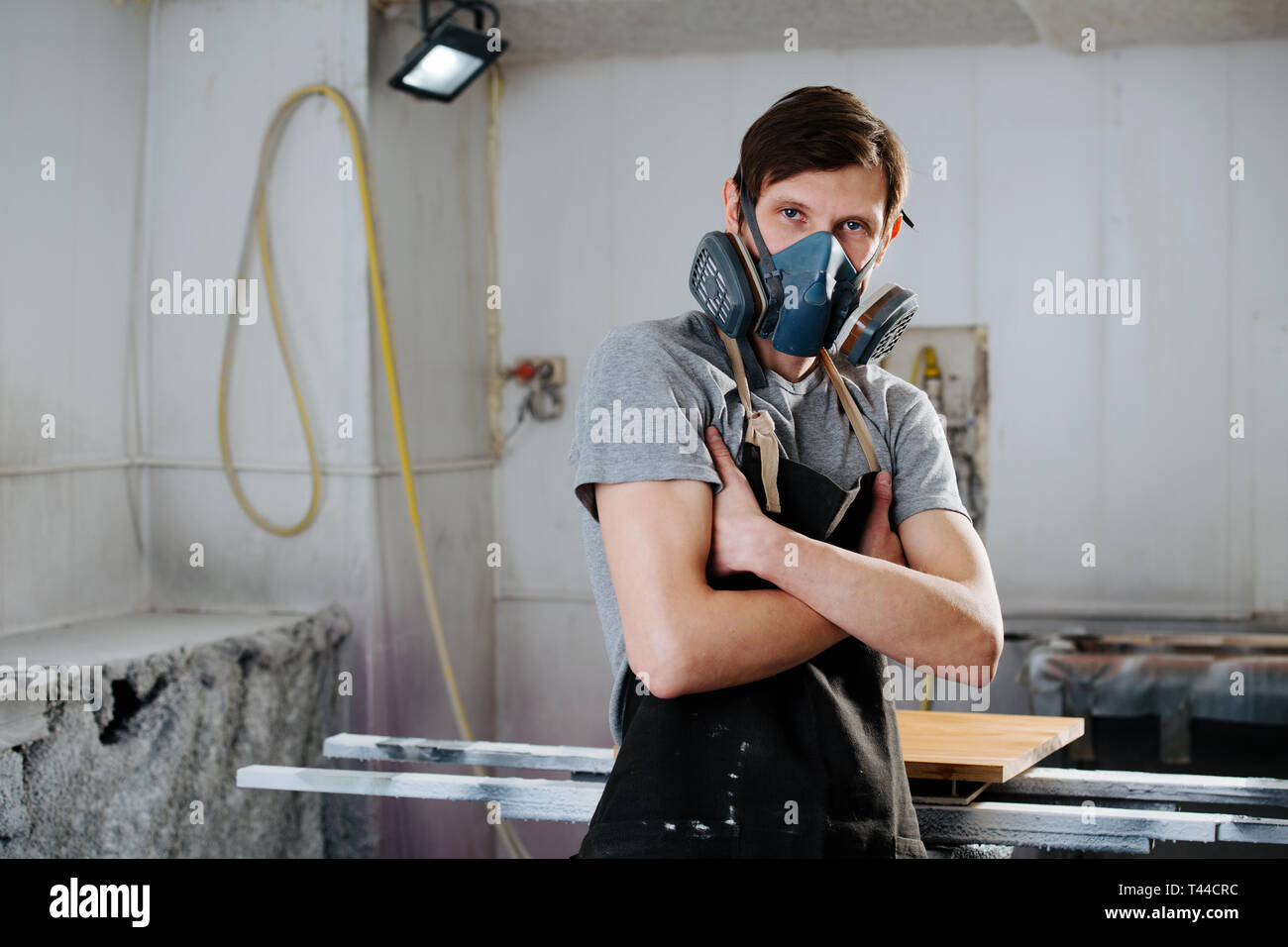 Ritratto di lavoro slim bello di mezza età brunet carpenter nel respiratore. Egli sta rendendo mobili su ordine in un workshop. In stato di fermo per una porta Foto Stock