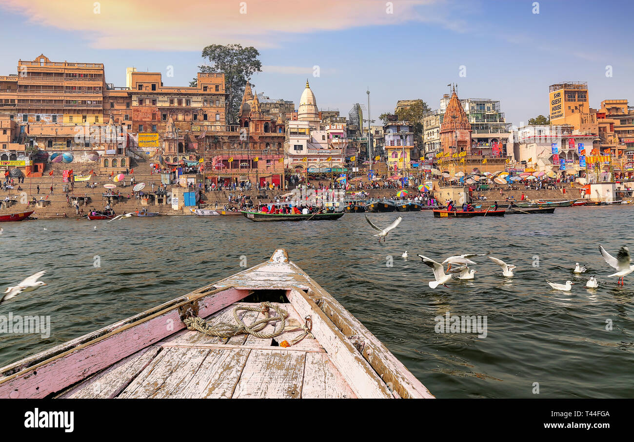 Varanasi antica India città architettura come visto da una barca sul fiume Gange con vista di uccelli migratori con moody Cielo di tramonto Foto Stock