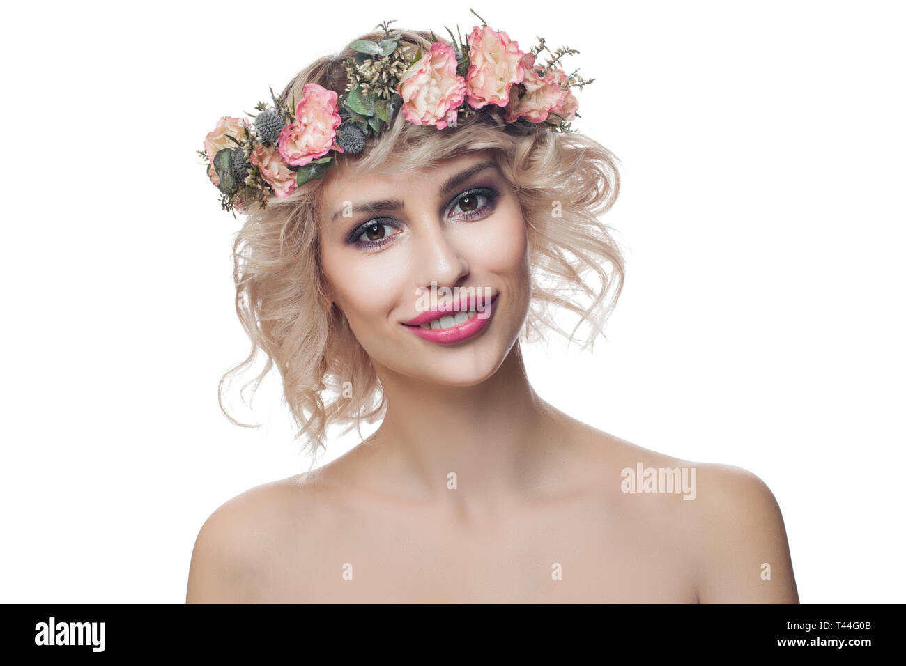 Bellissimo modello felice donna che indossa la corona di fiori isolati su sfondo bianco. Capelli ricci, trucco e fiori Foto Stock