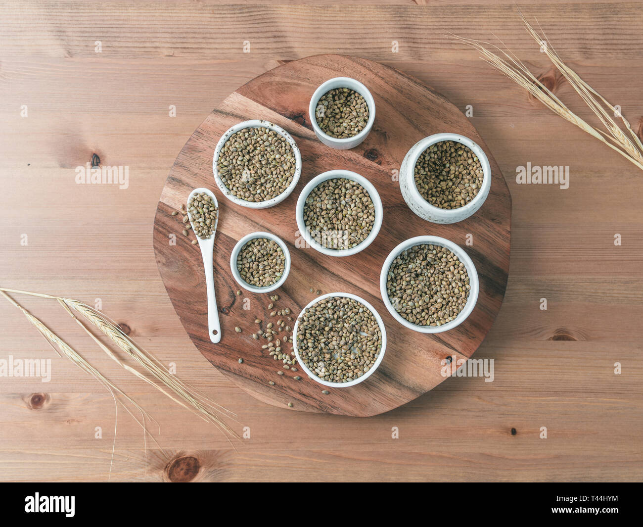 Sementi di canapa in piccole ciotole di bianco e il cucchiaio sul tavolo di legno. Set di piccole ciotole con organici grezzo grezzo di semi di canapa. Super e vegane concetto. Vista superiore o piatta lay.Copia spazio per il testo Foto Stock