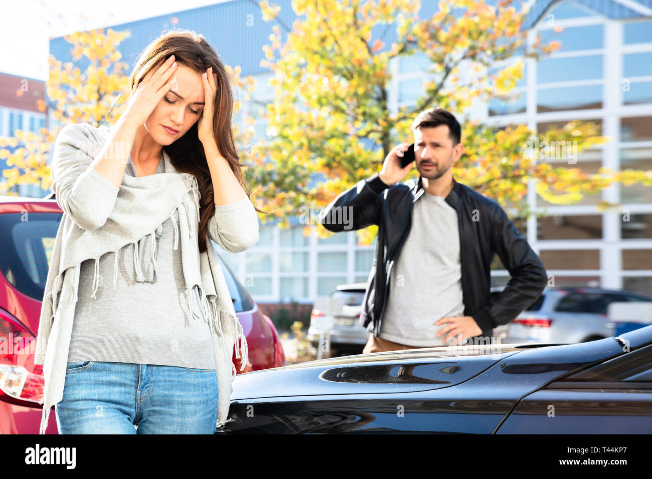 Uomo che chiamano per richiedere assistenza nella parte anteriore del triste donna cerca auto danneggiata su strada Foto Stock