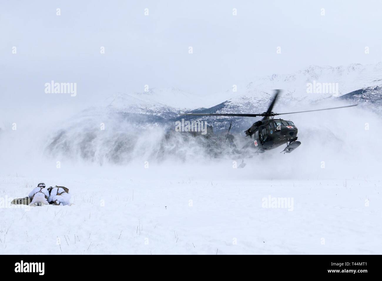 Stati Uniti Paracadutisti dell'esercito con il primo squadrone, quarantesimo reggimento di cavalleria (airborne), quarta brigata di fanteria combattere Team (airborne), XXV divisione di fanteria, U.S. Esercito di Alaska, Huddle per proteggere un finto incidente dal rotore-lavaggio di un atterraggio UH-60 Black Hawk elicottero a base comune Elmendorf-Richardson in Alaska, il 20 febbraio, 2019. Gli spartani teamed in su con i soldati da Golf Company, di distacco 2, 2° Battaglione, 104th supporto generale del battaglione di aviazione, JBER, per convalidare le loro capacità di evacuazione medica. Foto Stock