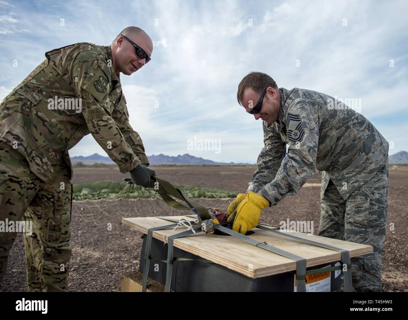 Stati Uniti Air Force Capt. Geremia Johnson e Chief Master Sgt. Il Ciad Mero annulla le cinghie a basso costo di bassa altitudine (LCLA) apparecchiature immediatamente dopo un airdrop presso lo Yuma Proving Grounds, Ariz. Febbraio 26, 2019. Questo anno di funzionamento Snowbird esercizio consisteva di un multi-stato aviation partnership tra la 133e 182nd Airlift ali, in preparazione per le future distribuzioni d'oltremare. Foto Stock