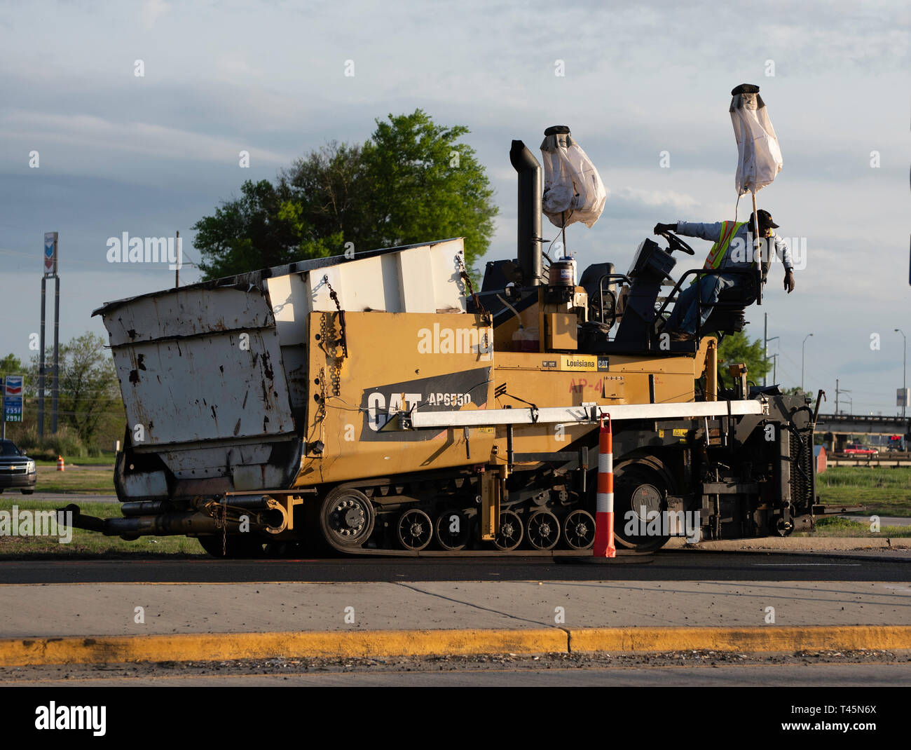 BOSSIER CITY, LA., U.S.A. - 12 Aprile 2019: un lavoratore opera un pezzo di attrezzature pesanti come procede il lavoro su un U.S. Autostrada 80 progetto di ripavimentazione. Foto Stock