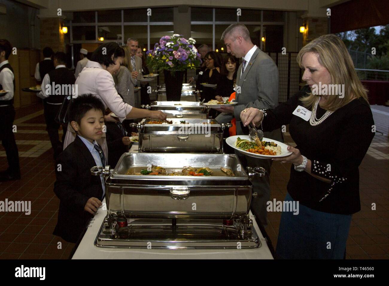 Gli ospiti servire essi stessi la cena durante la donna americana di Welfare Association (AWWA) e Marine Officers' CONIUGE' Club Okinawa amicizia sociale su Camp Butler, Okinawa, in Giappone Mar. 2, 2019. Il Socio è tenuto ogni anno per celebrare le organizzazioni che hanno ricevuto i fondi delle sovvenzioni e fornire la consapevolezza circa AWWA per entrambi gli Stati Uniti e la comunità locale. AWWA ha già contribuito con oltre 75 mila dollari per Giapponese e organizzazioni americane quest'anno fiscale. Foto Stock