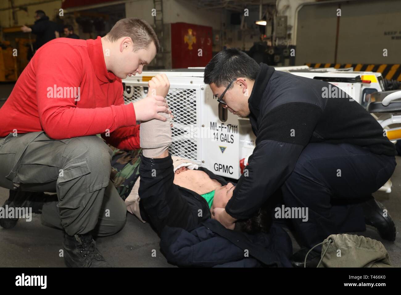 OCEAN (Mar. 4, 2019) Aviation Ordnanceman 3rd Class Rannen Woodworth e Hospital Corpsman 3rd Class Drew Aligsao amministrare primo aiuto durante un incidente di massa praticare nell'hangar bay a bordo l'assalto anfibio nave USS Bataan (LHD 5). La nave è in corso conduzione di esperimenti in mare. Foto Stock