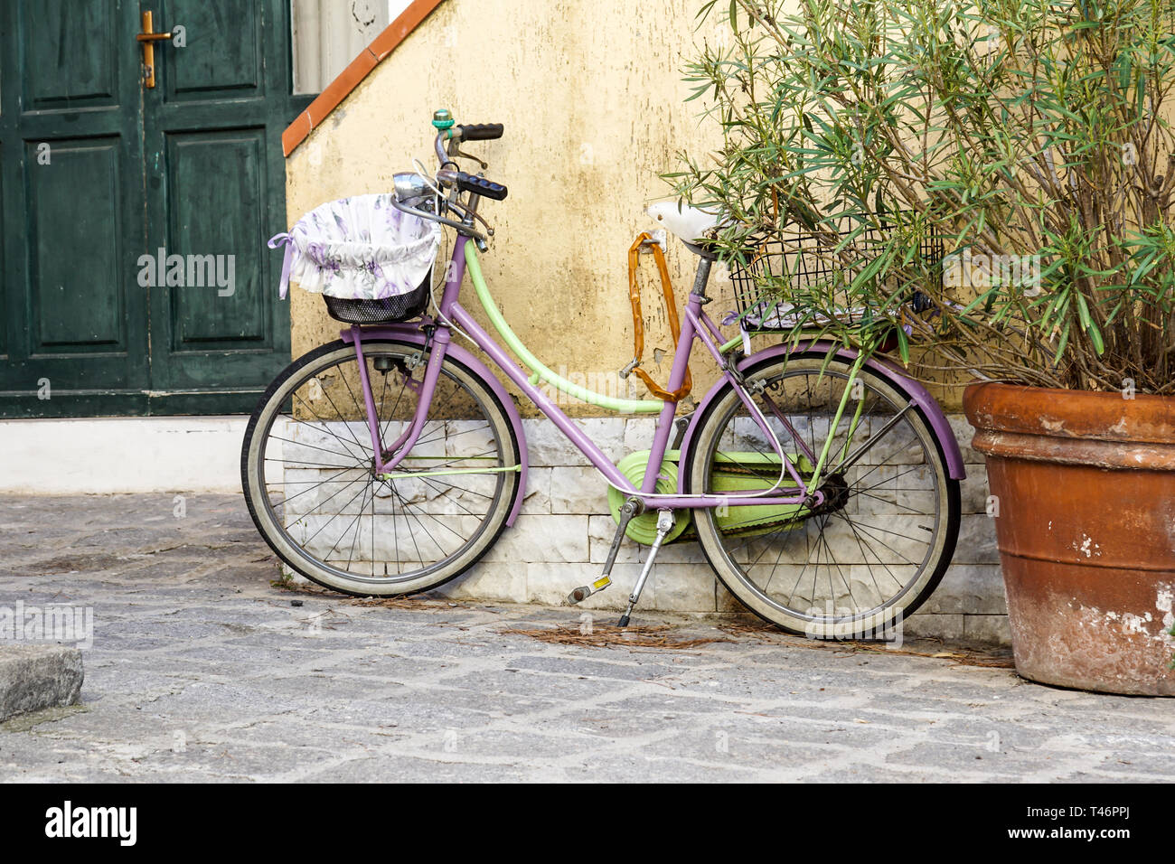 Una donna di bicicletta è legato ad un palo di ferro. Nelle vicinanze vi è la cornice rossa di un sito in costruzione. Foto Stock