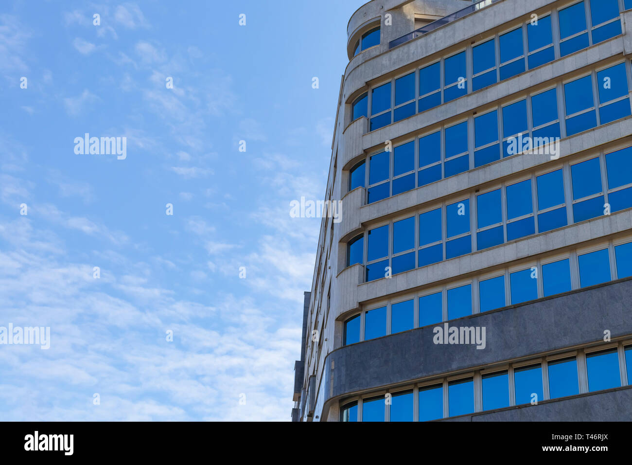 Moderno edificio residenziale di vetro e cemento contro un cielo blu Foto Stock