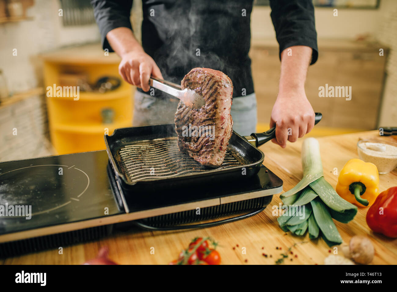 Persona di sesso maschile la cottura della carne in una padella in cucina Foto Stock