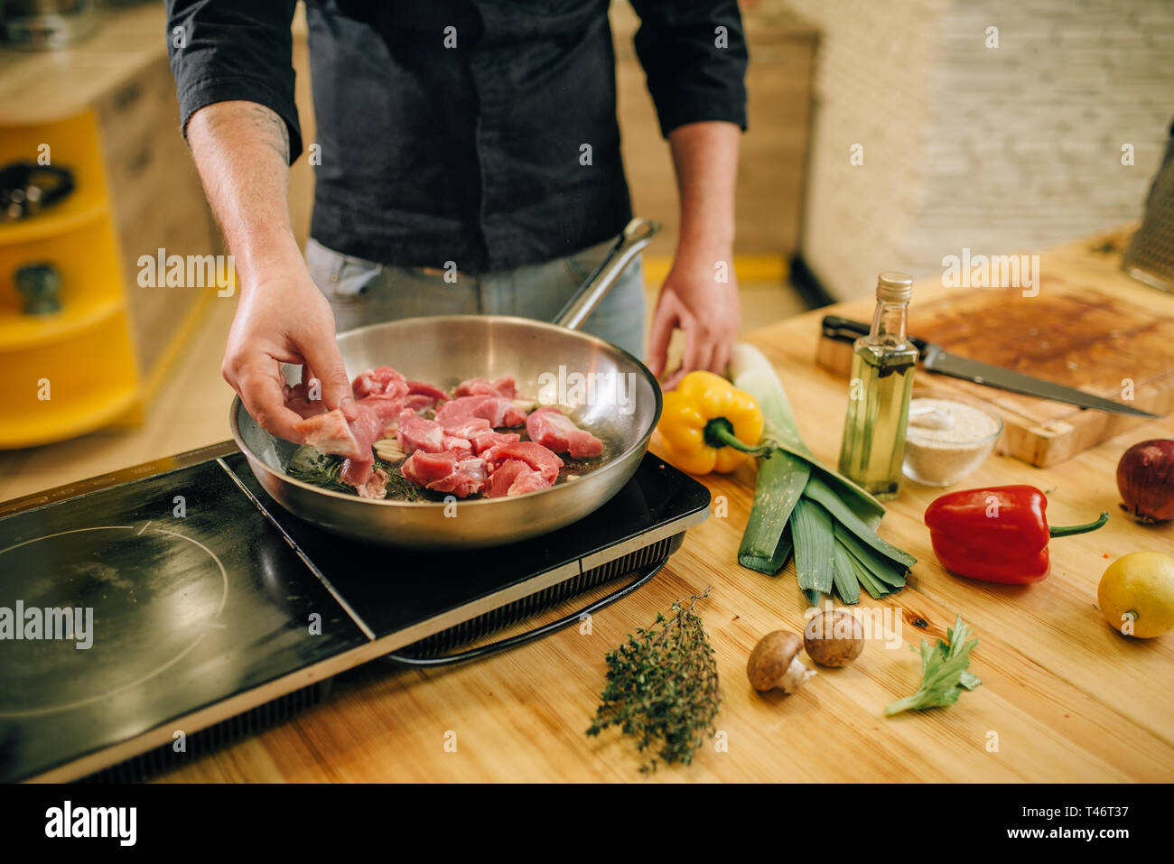 Persona di sesso maschile per la cottura della carne con erbe in una padella Foto Stock