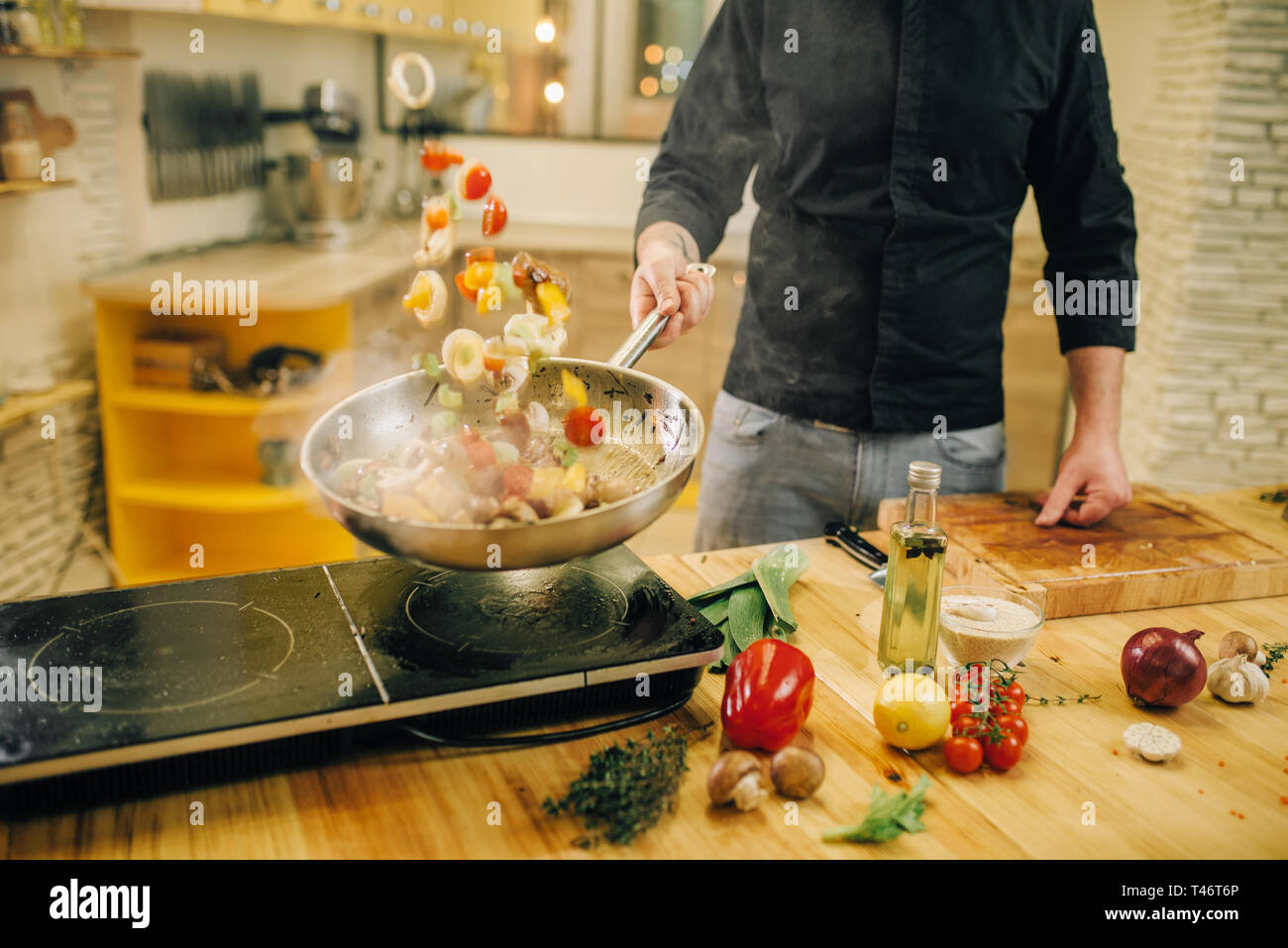 Lo chef maschio per la cottura della carne con vetables in padella Foto Stock