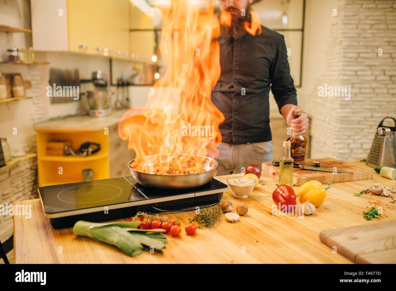 Lo chef maschio per la cottura della carne con vetables sul fuoco Foto Stock