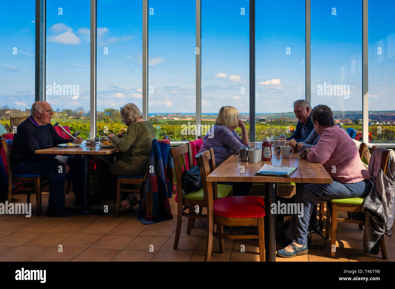 Le persone che si godono il tè del pomeriggio in corrispondenza della finestra sedi in Abbazia Visualizza Café con vedute di Whitby all Abbazia Foto Stock