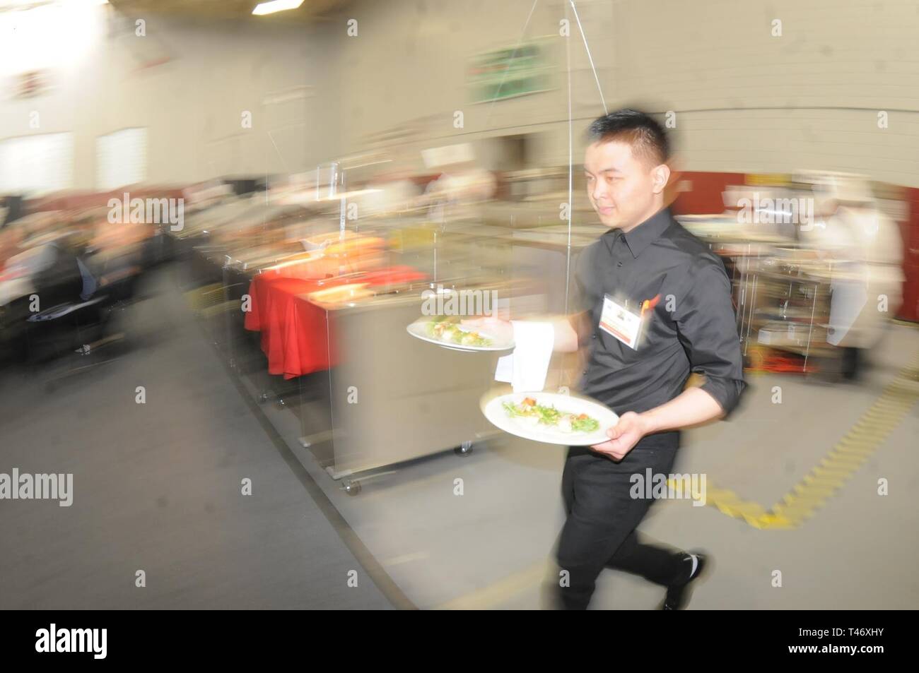 Airman 1. Classe Charles Camantique, Base comune Lewis-Mccorda, affretta a servire i clienti durante il militare cibo caldo cucina sfida Marzo 12. Foto Stock
